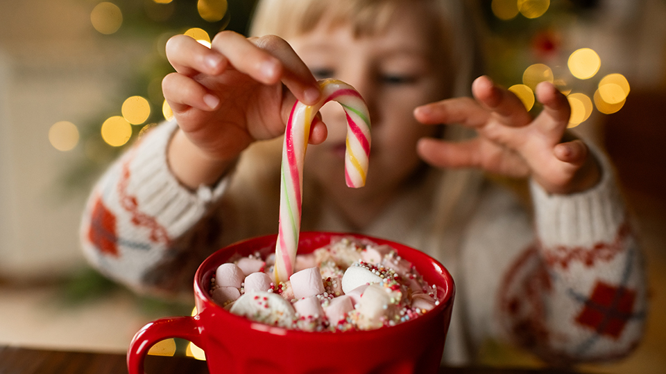 Little girl with a mug of hot chocolate and candy in Christmas