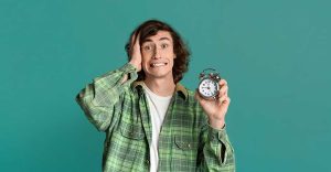 Teen boy with alarm clock scared of being late on turquoise background