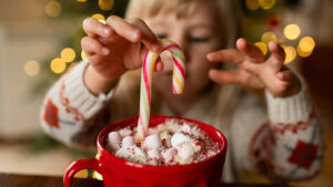 Little girl with a mug of hot chocolate and candy in Christmas