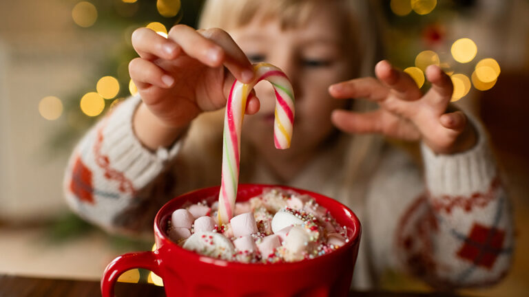 Little girl with a mug of hot chocolate and candy in Christmas