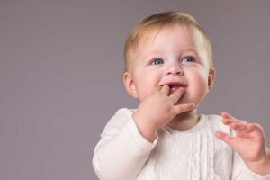 Baby showing signs of teething while chewing on fingers