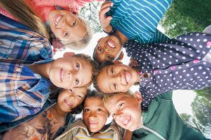 Group of seven smiling children looking down at the camera, illustrating healthy smiles and children's dental health.