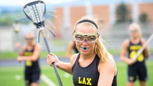 teen girl playing lacrosse wearing a protective sports mouthguard
