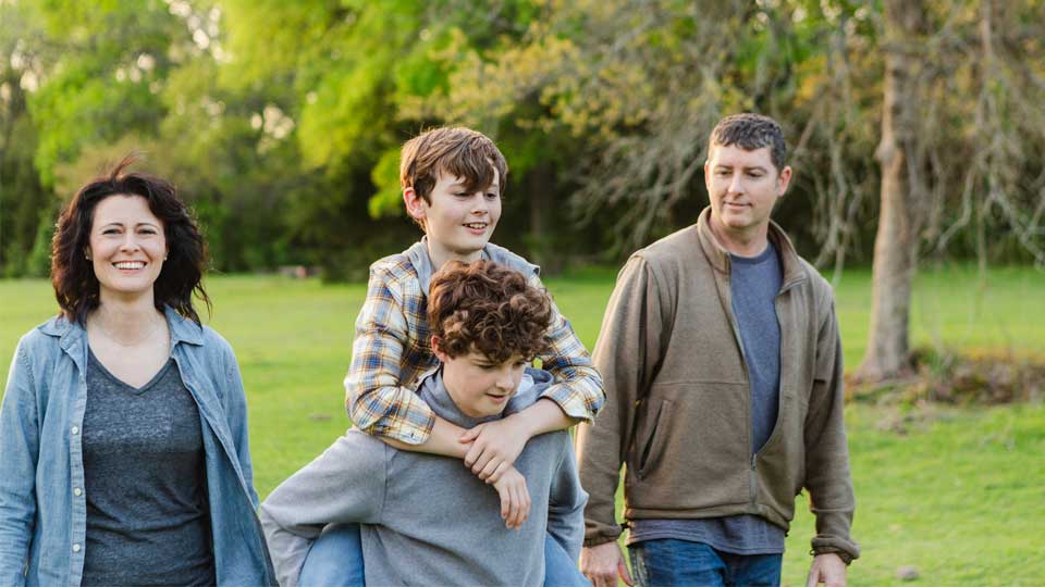 Teen boys walking outdoors with their parents, representing family support, teen dental health, and ongoing pediatric dental care during adolescence.